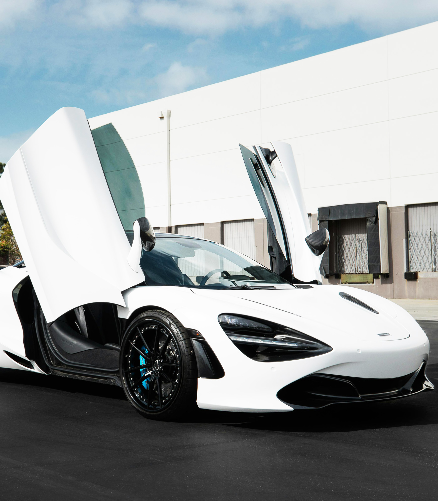 Manufacturing high-performance components for the luxury automotive industry, showcased by a modern white supercar with its butterfly doors open.