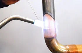 Industrial brazing of a copper tube using a gas torch and a silver-based filler metal to create a high-integrity joint for manufacturing.