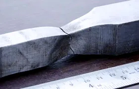 This is a photograph of a real metal specimen after it has been subjected to a tensile test and broken.