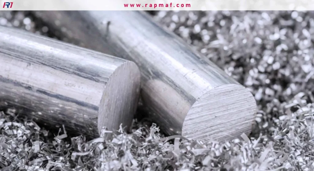 This image displays finished or semi-finished aluminum products in the form of solid cylindrical bars (billets). The bars are resting on a bed of metal shavings (swarf), which are byproducts of machining processes like cutting or lathing. This represents aluminum after it has been melted, cast, and processed into a usable form.