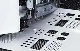 Um close de uma prensa puncionadeira CNC perfurando com precisão padrões geométricos complexos e furos em uma folha de metal.