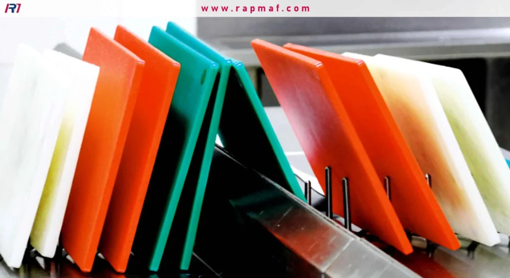 Colorful sheets of HDPE plastic in white, orange, and teal, organized vertically in a metal rack, showcasing material stock for custom fabrication.