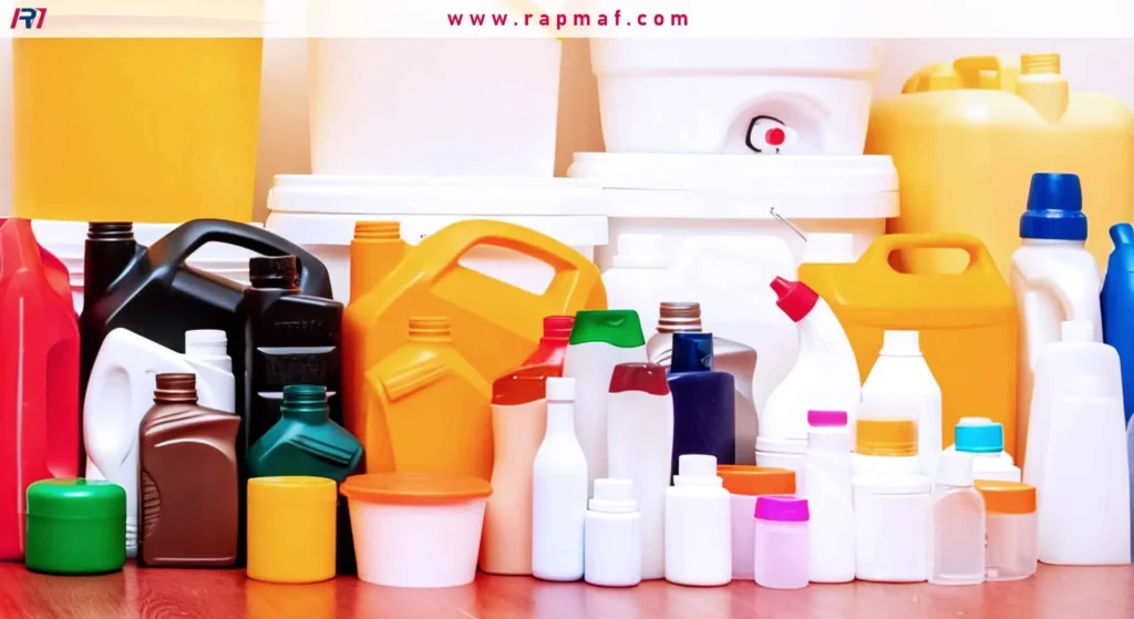 An assortment of various plastic containers, including large yellow and white industrial jugs, buckets, and bottles, arranged on a wooden surface