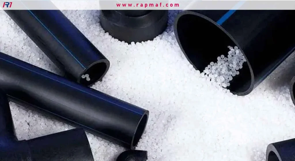 Black HDPE pipes and fittings resting on a bed of white plastic raw material pellets, illustrating the connection between the base material and the finished product.