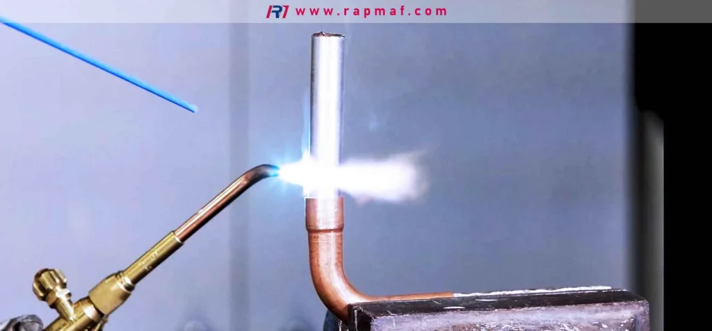 The process of torch brazing, where a high-temperature flame heats a copper pipe joint to allow a filler rod to melt and flow into the gap via capillary action. This method, highlighted by Rapmaf, joins materials without melting them, making it ideal for applications like HVAC.