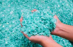 Close-up of shredded PET plastic chips, showcasing the primary form of recycled polyester before it is melted and extruded in the manufacturing process.