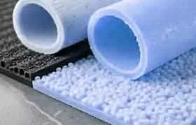 Close-up de chapas texturizadas de TPE em cores diferentes. Uma chapa azul-clara com superfície granulada e rugosa está em primeiro plano, com uma chapa preta com padrão quadriculado atrás.