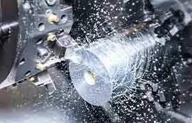 Um close de um torno CNC girando uma peça de metal, com uma ferramenta de corte removendo material ativamente enquanto o fluido refrigerante espirra para todos os lados.