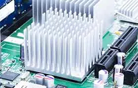 Um close-up de um dissipador de calor de alumínio prateado com aletas montado em um chip em uma placa de circuito eletrônico verde para resfriamento passivo.