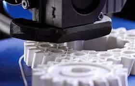 O processo de manufatura aditiva em ação: uma cabeça de impressora 3D construindo precisamente um protótipo personalizado de uma engrenagem de plástico branco, camada por camada.