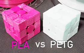 Dois cubos idênticos impressos em 3D com materiais diferentes: o rosa em PLA e o branco em PETG. Isso demonstra como a escolha do material afeta a aparência e a textura da peça final.
