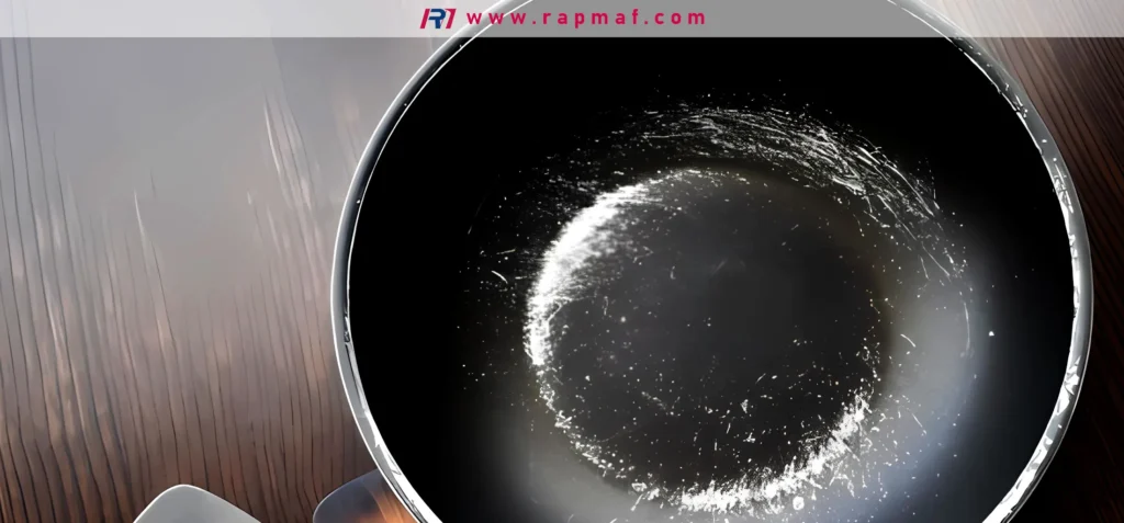 An overhead shot of a worn-out non-stick frying pan with significant scratches, raising concerns about the degradation of the PTFE surface and the potential for ingesting coating particles.