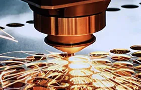 Die Düse eines Faserlaserschneiders im Betrieb: Sie verdampft Metall, um komplexe Formen aus einem Metallblech auszuschneiden, wobei geschmolzenes Material einen Funkenregen erzeugt. Dies verdeutlicht die hohe Energiedichte des Laserschneidprozesses.