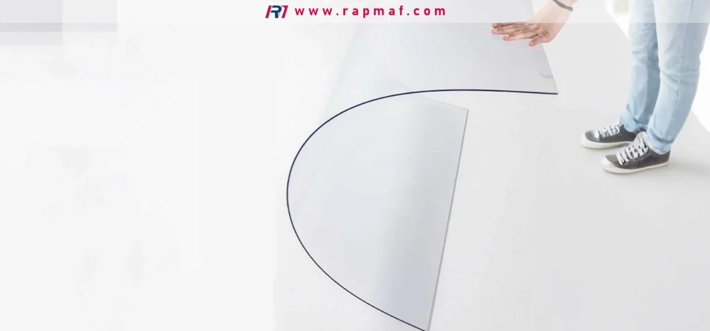 Demonstration of polycarbonate's flexibility and toughness, as a large, clear sheet is bent into a gentle curve without breaking or cracking, highlighting its superior impact strength.