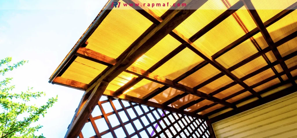 An outdoor application of translucent polycarbonate roofing panels on a wooden pergola, showing signs of material degradation and yellowing after prolonged exposure to sunlight and the elements.