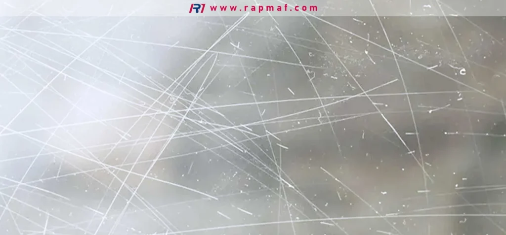 A magnified view of a polycarbonate surface exhibiting extensive damage in the form of numerous fine scratches, a direct result of its low surface hardness compared to materials like glass or acrylic.