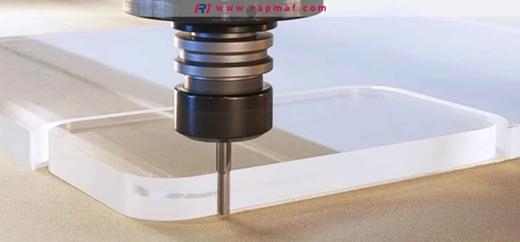 The spindle and end mill of a CNC router cutting a contour into a piece of cast acrylic block, showcasing the fabrication of a custom PMMA component by a precision manufacturing service like Rapmaf.