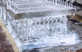 Galvanização a quente de componentes de aço. Um dispositivo que segura várias peças é retirado de um banho de zinco fundido, permitindo que uma ligação metalúrgica se forme e crie um revestimento de zinco durável e de sacrifício.