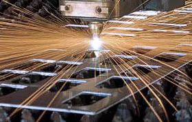 A close-up of a fiber laser cutting machine performing a high-speed profile cut on a steel plate. The intense energy creates molten metal and sparks, demonstrating a core process in metal fabrication.