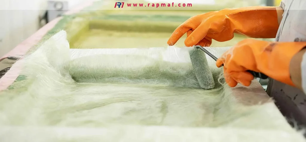 The manual lamination process of creating a Fiber-Reinforced Plastic (FRP) component. A technician uses a laminating roller to ensure proper wet-out of the fiberglass reinforcement with polyester or epoxy resin in a composite mold.
