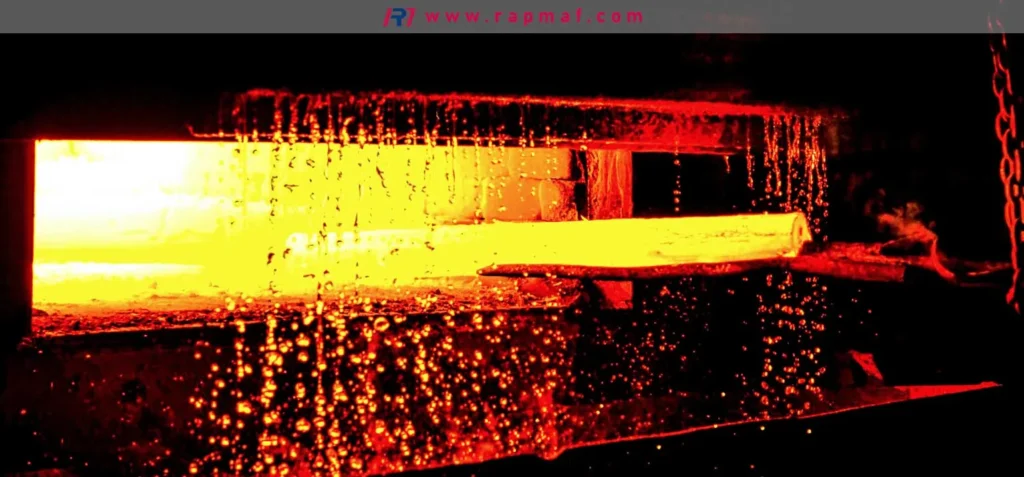 Una barra de acero incandescente se extrae de un horno de tratamiento térmico industrial en Rapmaf. Este calentamiento controlado es el primer paso del proceso de recocido o revenido para aliviar tensiones, que previene la deformación en componentes mecanizados de precisión.