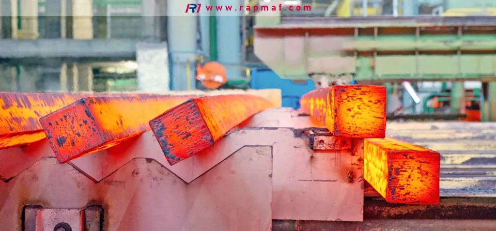 Una línea de palanquillas de acero al rojo vivo se desplaza por una cinta transportadora tras ser calentadas en un horno. Este proceso, conocido como normalización o alivio de tensiones, es fundamental para estabilizar la microestructura del material antes de que Rapmaf lo mecanice en piezas de precisión, lo que previene la deformación posterior al mecanizado.