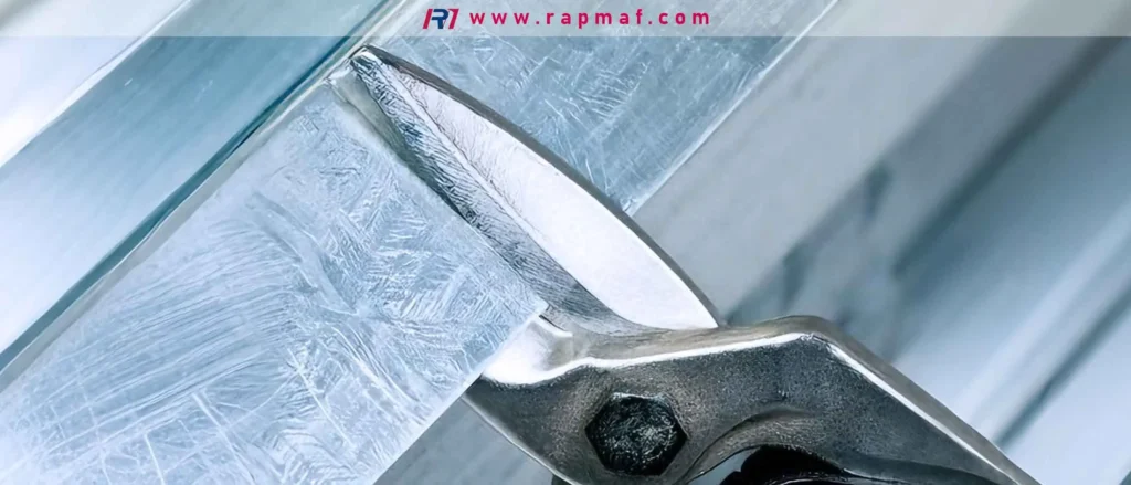 A close-up of heavy-duty tin snips making a precise, clean cut through a piece of galvanized sheet metal. This manual tool is evaluated by Rapmaf for its accuracy on thin-gauge materials.