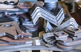 Large stacks of newly fabricated sheet metal parts from Rapmaf, including laser-cut plates and bent steel brackets, ready for the next stage of production or assembly, showcasing high-volume manufacturing capability.