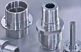 Una colección de piezas personalizadas complejas y de alta precisión mecanizadas por CNC a partir de acero inoxidable, que presentan características intrincadas como bridas, ejes escalonados y orificios perforados que requieren una fabricación experta.