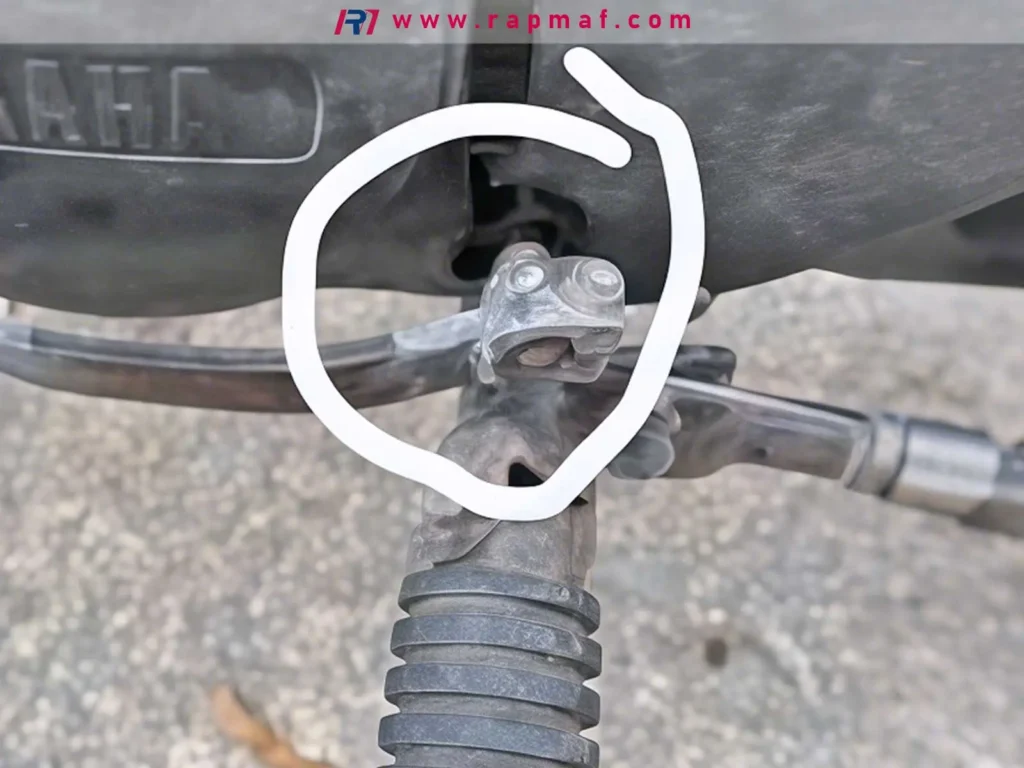 A close-up photo of a metal linkage on a machine, with a white circle drawing attention to the pivot point where forces are transferred.