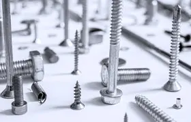 Una imagen en blanco y negro de primer plano de varios tipos de tornillos y pernos de metal colocados sobre una superficie blanca, creando un "paisaje urbano" de sujetadores.