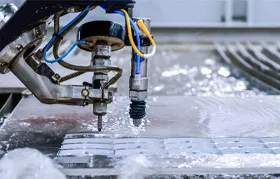 A CNC abrasive waterjet cutting multiple small rectangular parts from a single sheet of metal, illustrating how efficient part nesting reduces material waste and overall project cost.