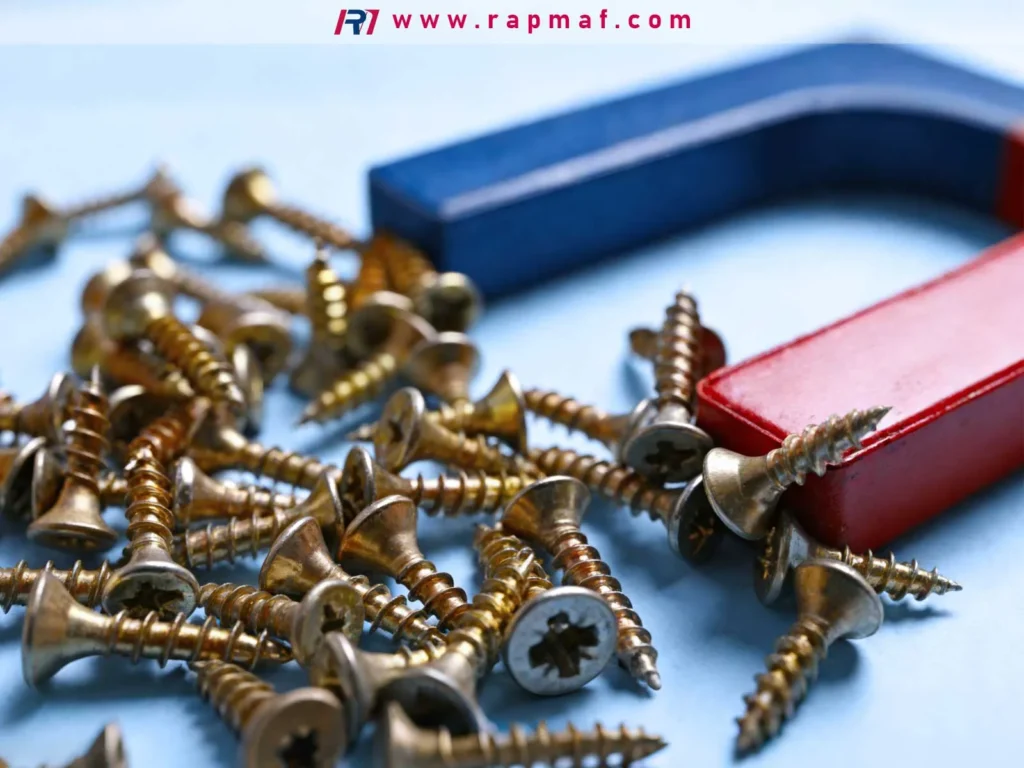 A magnet held over a pile of brass screws, demonstrating that brass, a non-ferrous copper alloy, is not magnetic—a key property to consider when choosing between brass and bronze.