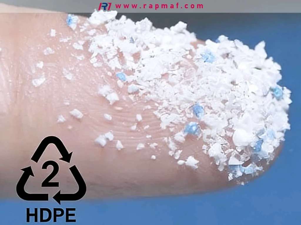 A close-up by Rapmaf of shredded HDPE plastic flakes on a fingertip, with the number 2 recycling symbol, highlighting the recyclability and sustainability of High-Density Polyethylene.