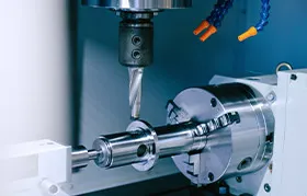 A CNC turn-mill center performing a cutting operation on a polished steel shaft, an example of a subtractive metalworking process that uses computer control for high precision.