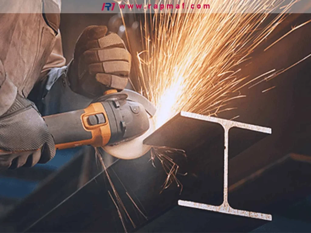 A metalworker using a handheld angle grinder with an abrasive cutting disc to cut through a steel I-beam, a basic and versatile cutting operation in metal fabrication. 
