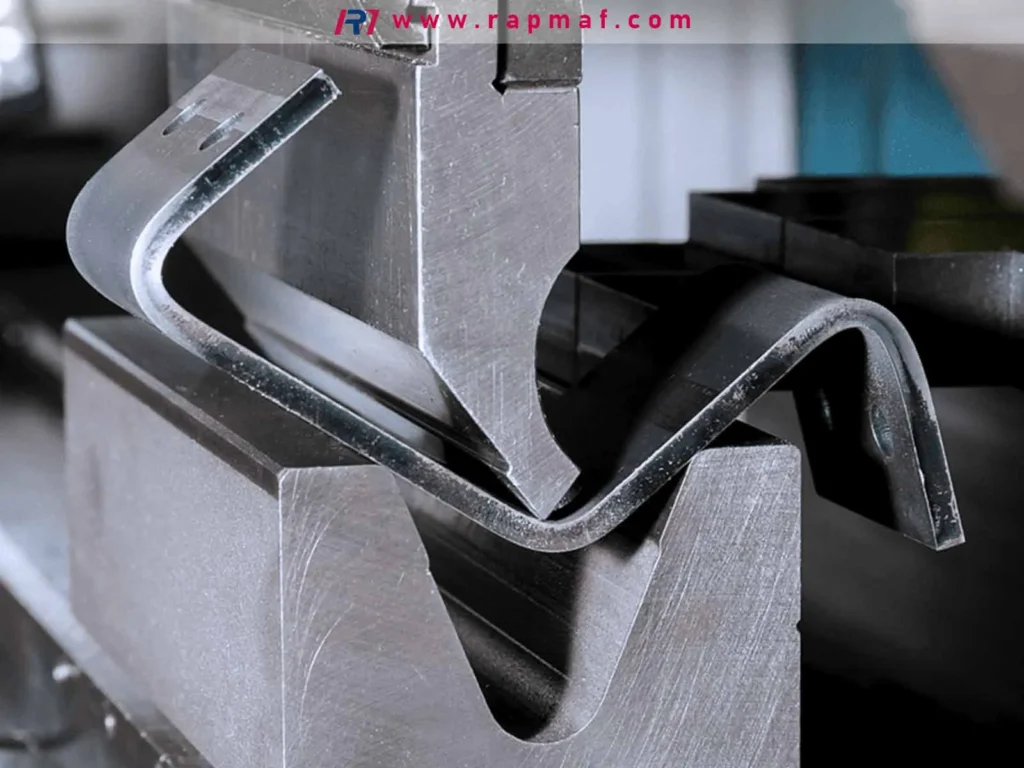 A close-up of a hydraulic press brake in action, a fundamental metal forming operation where a punch and die are used to precisely bend a sheet of metal into a desired angle.