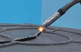 Close-up of an extrusion plastic welding tool repairing a crack in a thermoplastic part by laying down a bead of molten plastic filler material.