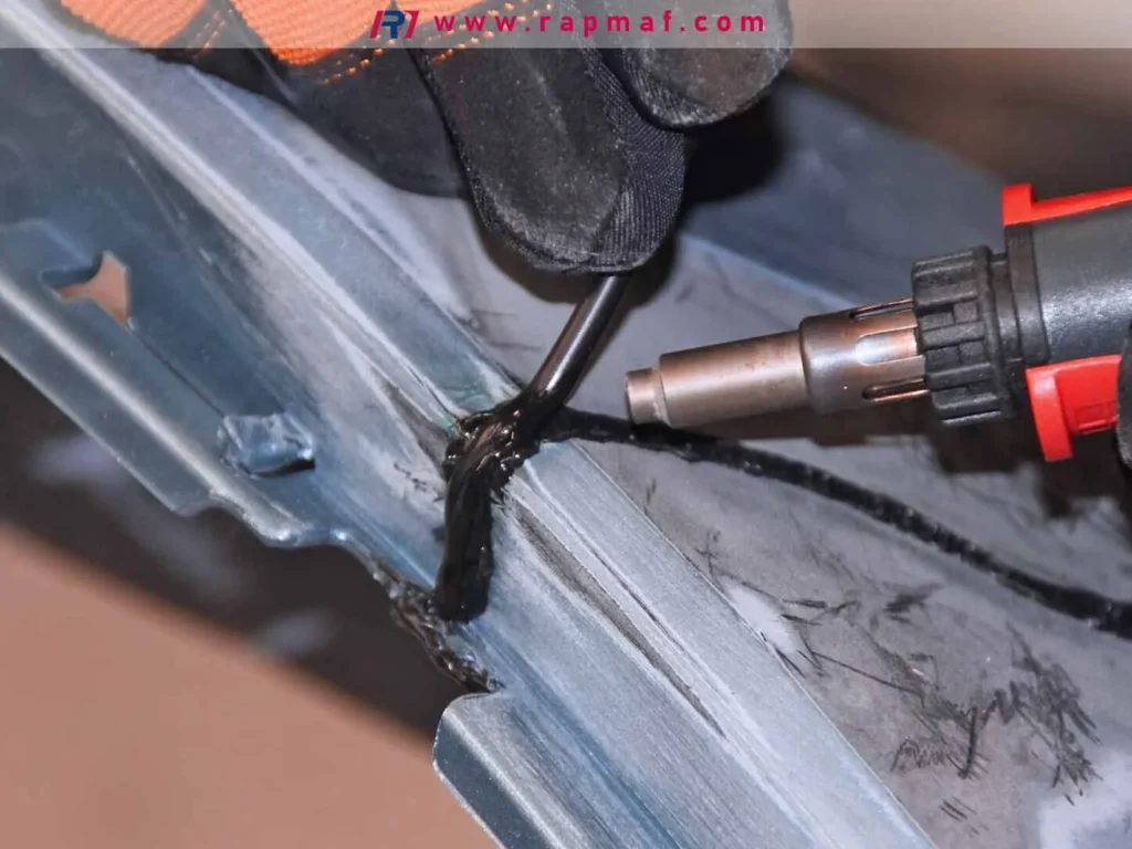 A practical example of plastic welding in the automotive industry, showing a technician using a hot air tool to apply a black plastic filler rod to repair a cracked car bumper.