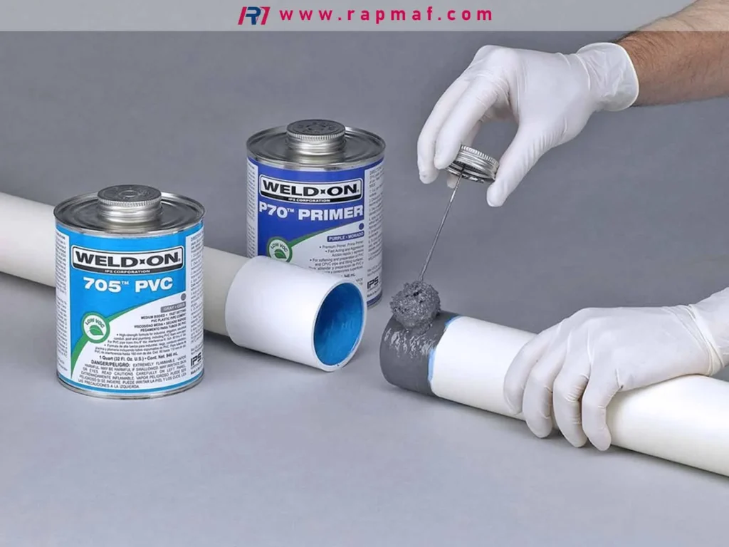 Demonstration of solvent welding, a chemical joining method for plastics, showing a technician applying purple PVC primer to a pipe before using cement to create a permanent bond.