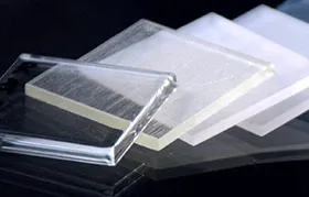 A collection of square engineering plastic samples, including clear (transparent) and frosted (translucent) acrylic or polycarbonate, used by engineers for material selection and prototyping.