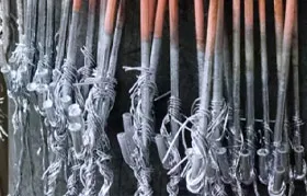 A close-up shot of metal parts hanging on industrial plating racks after being coated, showcasing a batch processing step in the metal plating or galvanizing industry.