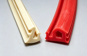A Rapmaf image comparing two different custom extruded rubber profiles, a white EPDM seal and a red silicone gasket, to demonstrate the versatility of elastomer manufacturing for creating complex, application-specific shapes.